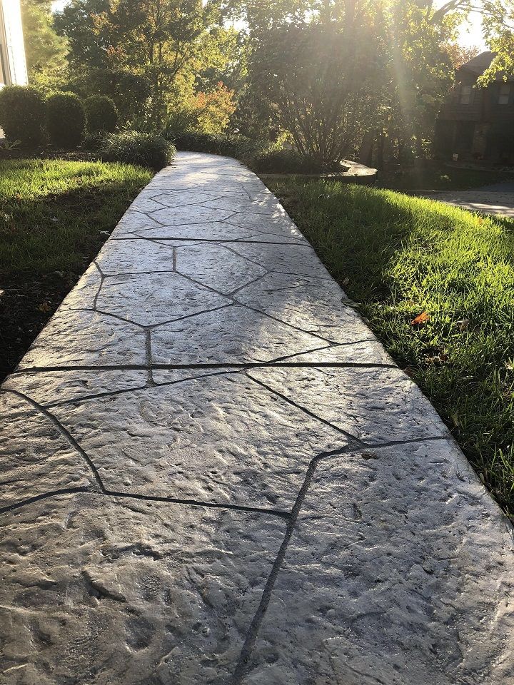 Stamped concrete walkway with green lawn in residential landscape