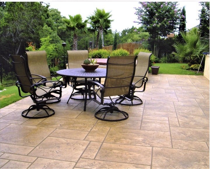 Outdoor patio with a round table and matching chairs arranged on a clean concrete surface
