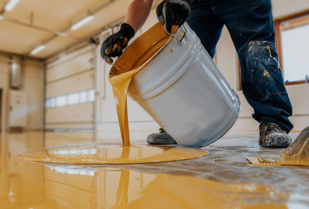 man pouring bucket of epoxy coating