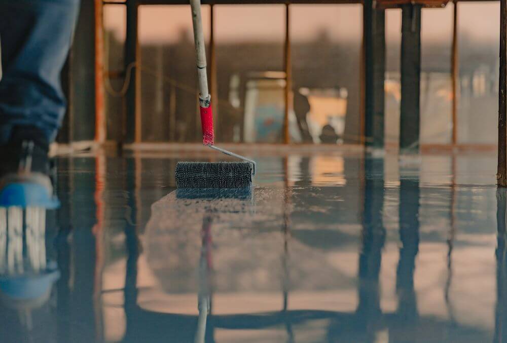 man applying an epoxy floor coating on the surface