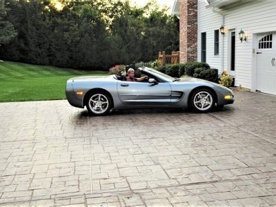 tamped concrete driveway with a parked convertible car in front of a modern home