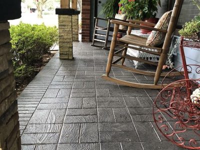 A wooden rocking chair placed on a stamped concrete patio with decorative texture