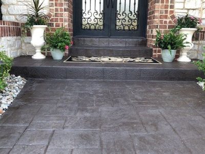 Front porch with dark stamped concrete flooring and decorative entry steps