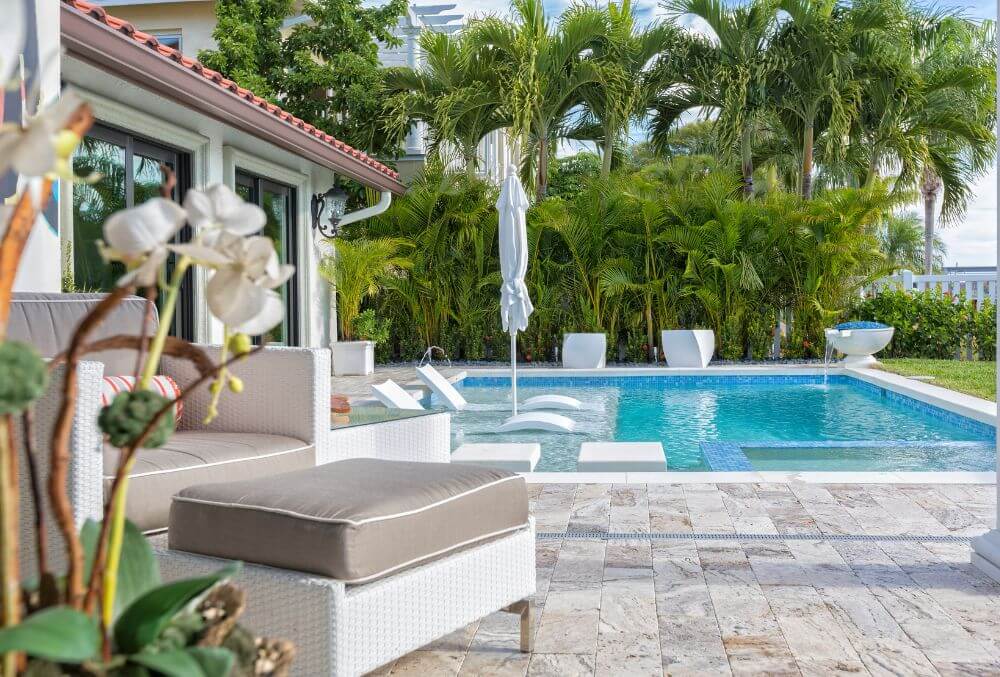 concrete pool deck with orchid plants and a chair
