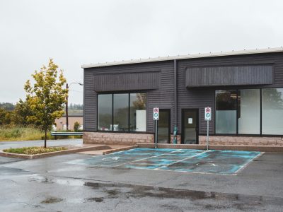 Wet concrete driveway in front of a modern commercial building with parking spaces and accessible parking area.
